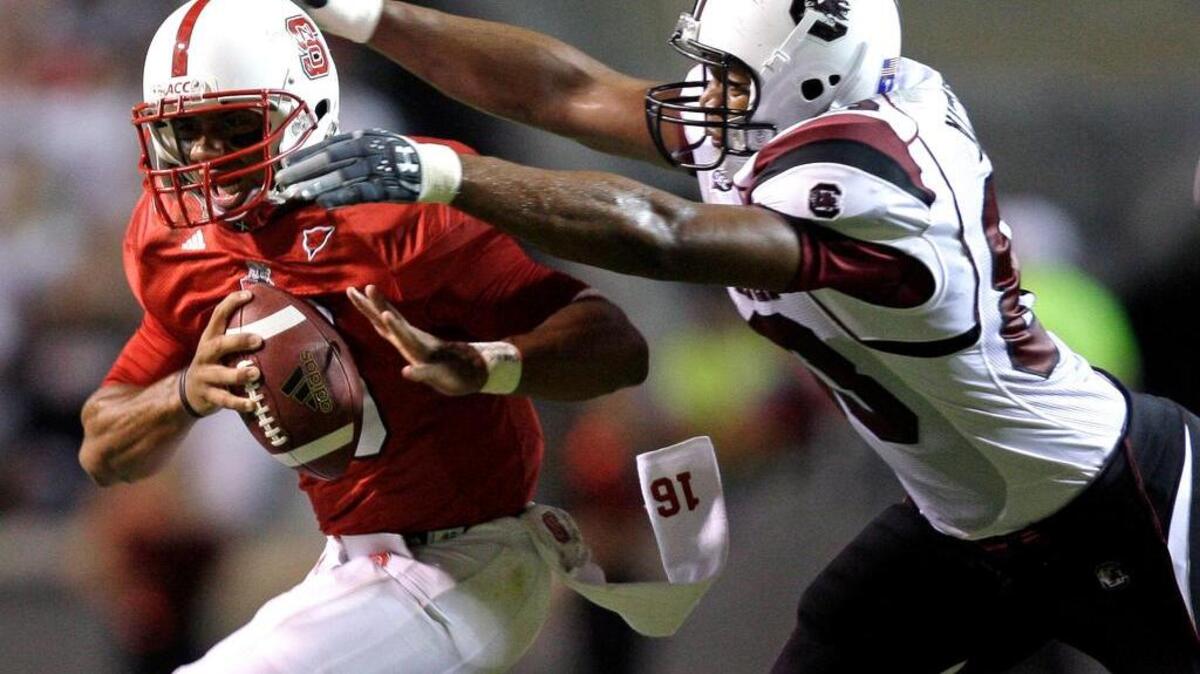 Then North Carolina State quarterback Russell Wilson, left, is chased down by South Carolina's Cliff Matthews during a game in 2009.