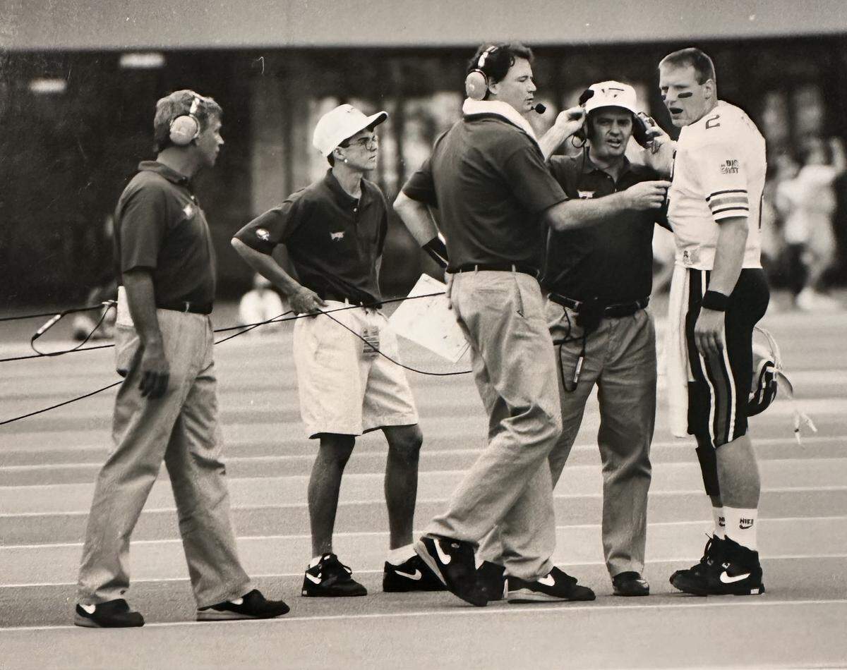 Shane Beamer (in shorts) holds the headset cable for his father, Virginia Tech coach Frank Beamer (second from right).