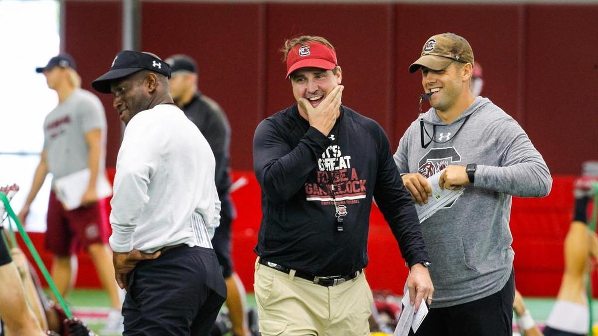 South Carolina football coaches, Travaris Robinson, Will Muschamp and Coleman Hutzler share a laugh during warmups before Gamecock football practice Wednesday.