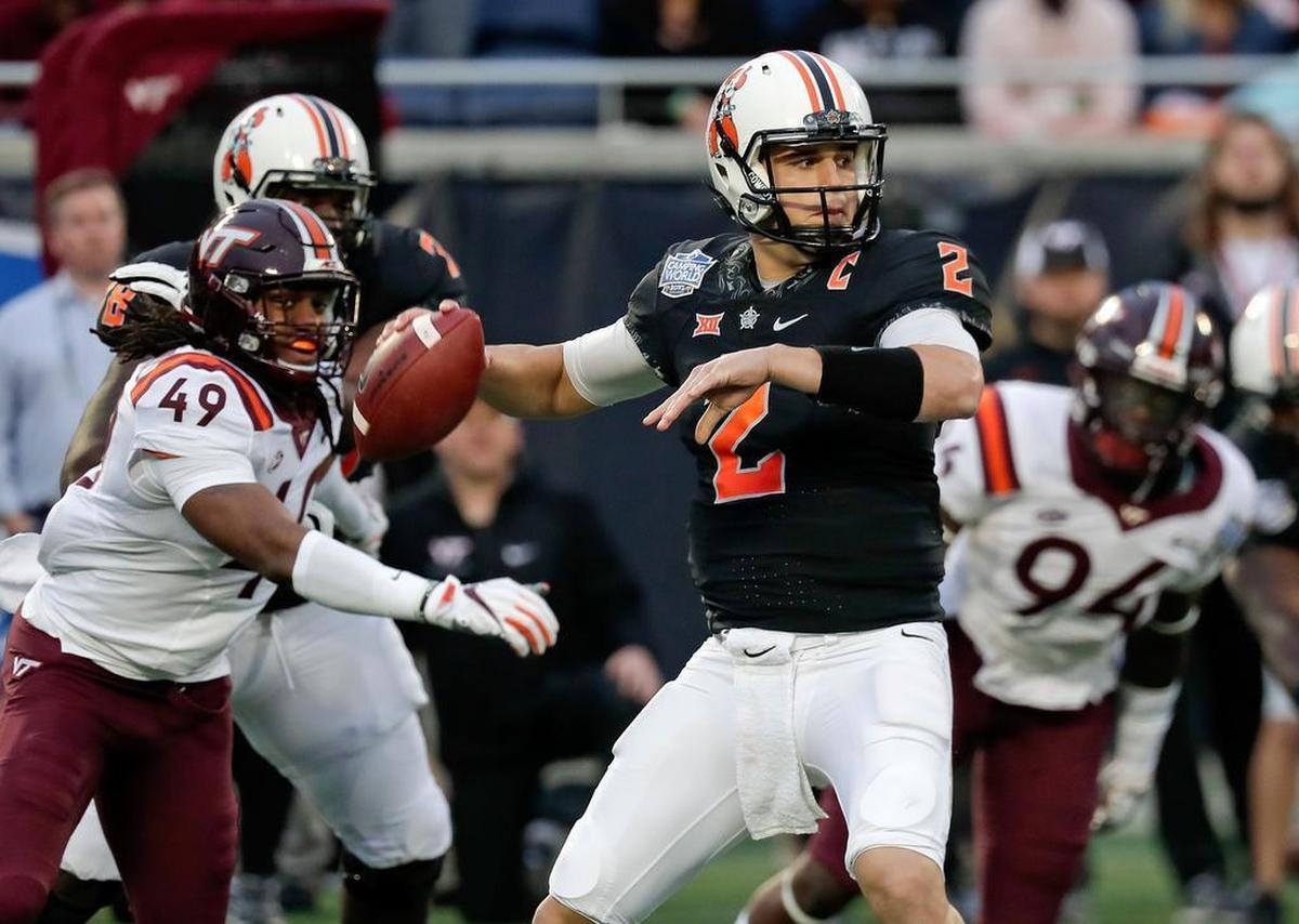 Oklahoma State quarterback Mason Rudolph (2) throws a pass as he is pressured by Virginia Tech linebacker Tremaine Edmunds (49) and defensive end Trevon Hill (94) during the first half of the Camping World Bowl NCAA college football game in Orlando, Fla.