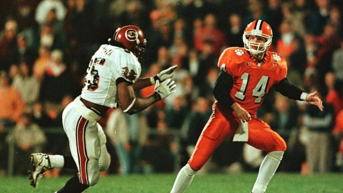 Clemson’s Brandon Streeter unloads a pass as John Abraham chases him down