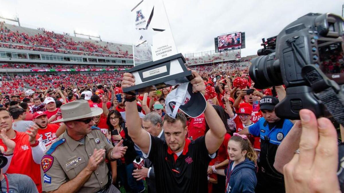 Houston's head coach Tom Herman holds the American West Trophy last week after the Cougars’ win over Navy.