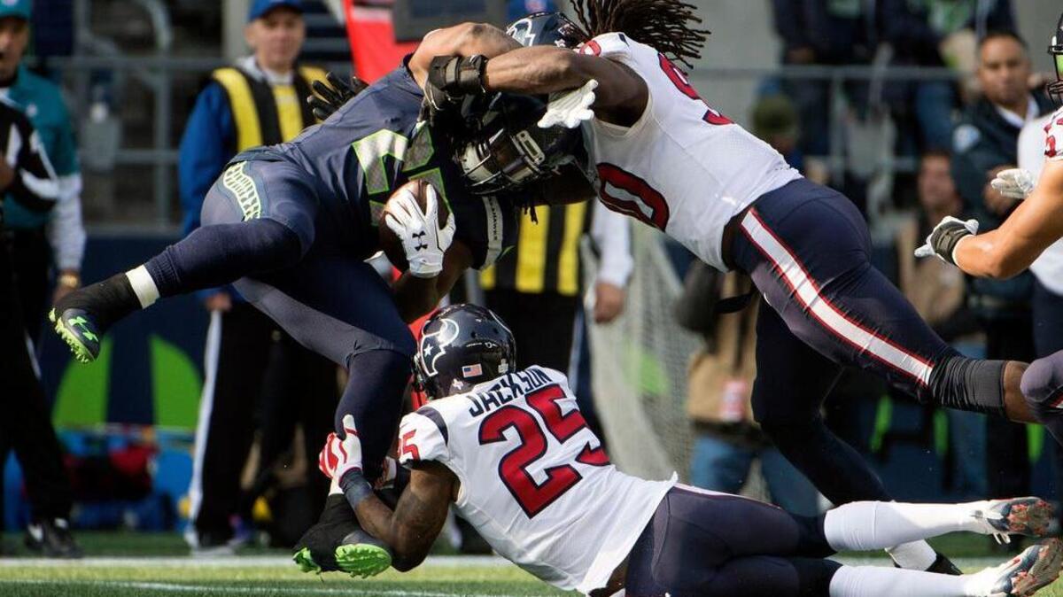 Seattle Seahawks running back Eddie Lacy (27) is tackled by Houston Texans cornerback Kareem Jackson (25) and outside linebacker Jadeveon Clowney (90) during the first half at CenturyLink Field.
