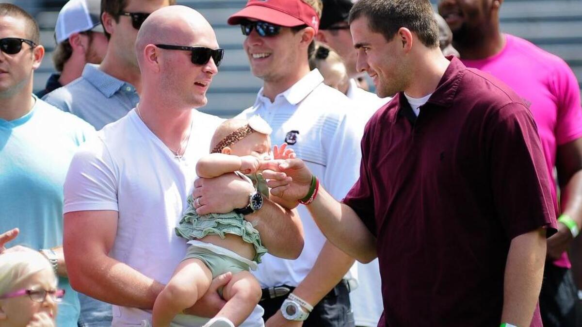 USC quarterbacks Connor Shaw (L) holds his daughter in 2015.