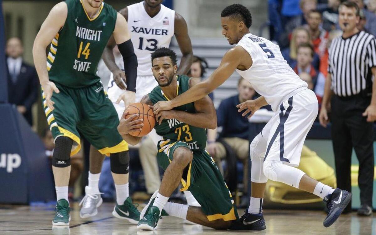 Wright State's Mark Alstork (23) stumbles on a drive as Xavier's Trevon Bluiett (5) reaches for the ball in 2015.