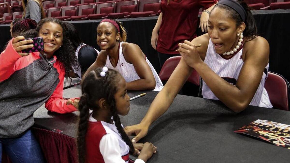 Jada Pearson 14, shoots a selfie with Tiffany Mitchell as A'ja Wilson entertains Jasmyn Graham, 5, at the autograph table.