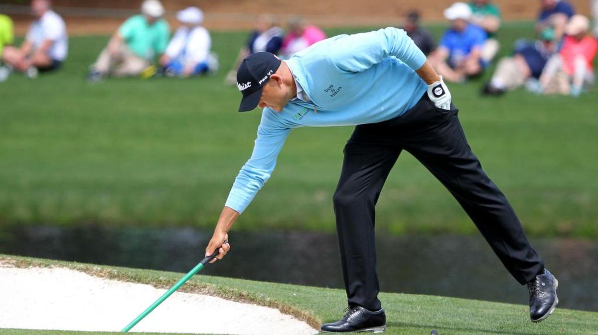 Bill Haas rakes a bunker during the Masters Par-3 Contest at Augusta National Golf Club.