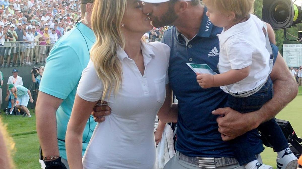 Dustin Johnson kisses fiance Paulina Gretzky while holding their son Tatum after winning the U.S. Open golf tournament at Oakmont Country Club.