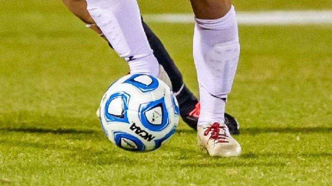 A soccer ball lands at the feet of an outfield player during a game.