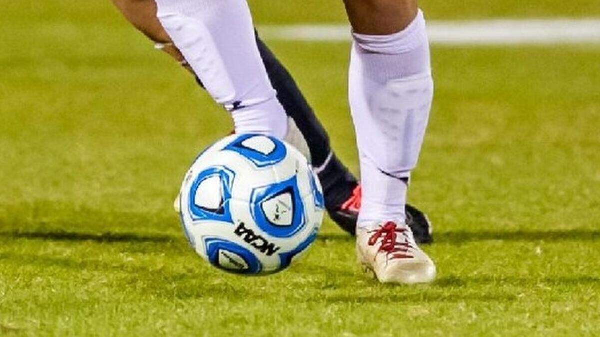 A soccer ball lands at the feet of an outfield player during a game.