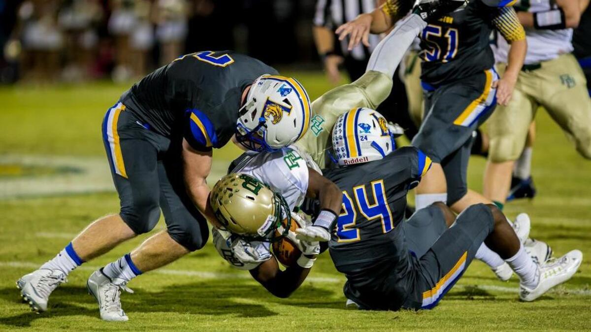 
Lexington's Trey Mitchell, left, and Michael Broadwater bring down River Bluff's Davon Johnson on Friday.
