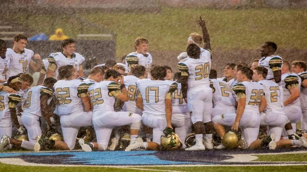 Before the scheduled game Friday between River Bluff and Chapin High, Gators player Bernard Larry (30) points to the sky as he and his teammates gather at midfield despite pouring rain in honor of teammate Lewis Simpkins, who collapsed and later died during a practice.