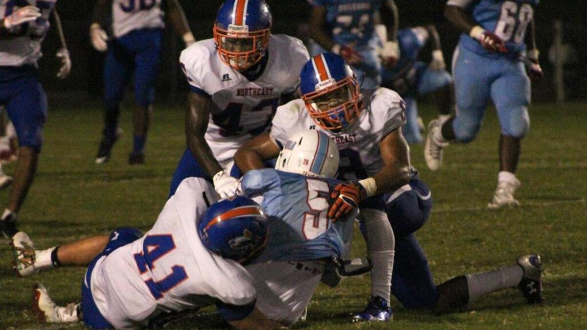 Richland Northeast’s Austin Howze, right, and Luke Lumbard, left, take down A.C. Flora running back Garrett Whetstone on Friday night.