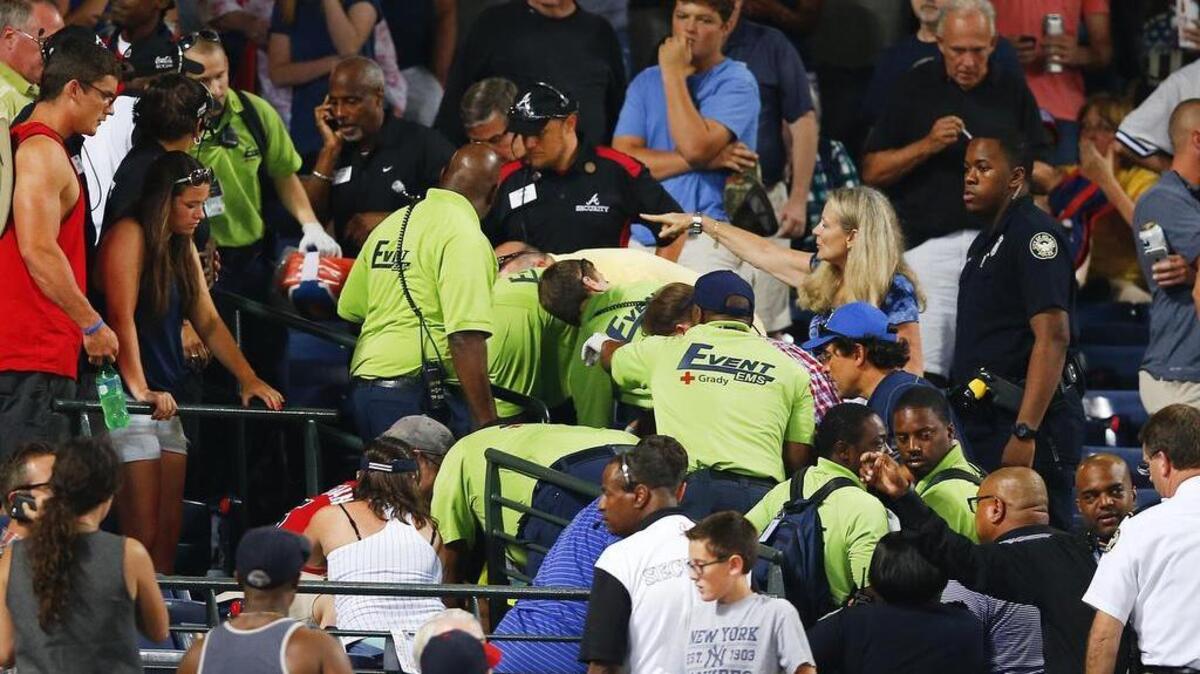 
Fans look on as emergency medical personnel work on a fan who fell from an upper deck at Turner Field during a game Saturday. The fan died later after reaching the hospital. 
