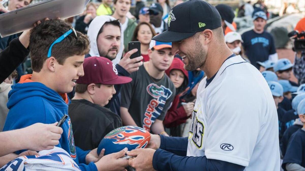 Tim Tebow signs autographs for fans.