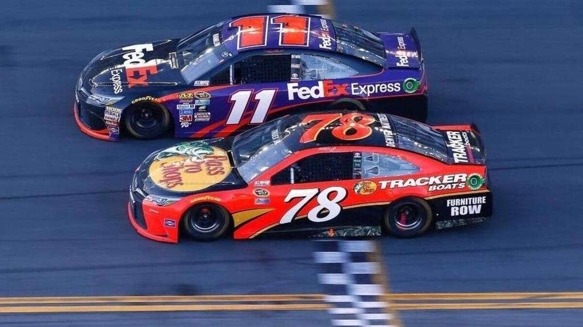 Denny Hamlin (11) takes the checkered flag ahead of Martin Truex Jr. (78) to win Sunday’s NASCAR Sprint Cup Series DAYTONA 500 at Daytona International Speedway.