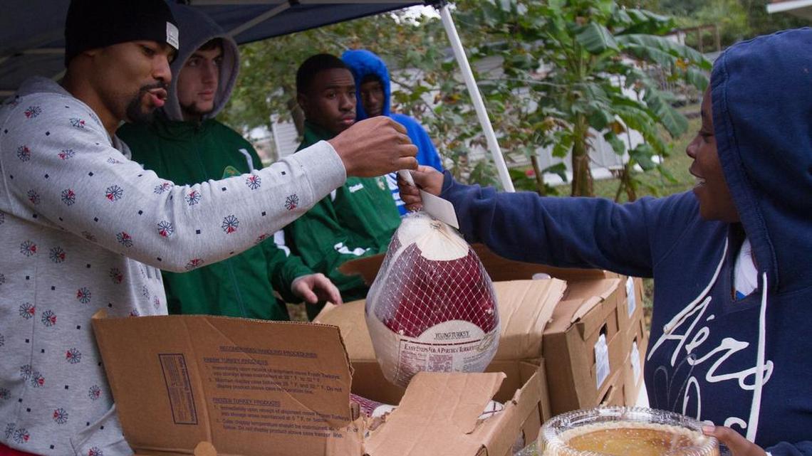 NBA player Ramon Sessions (left) hands out turkeys and other holiday items during his fifth annual event in the Racepath community, where he grew up.