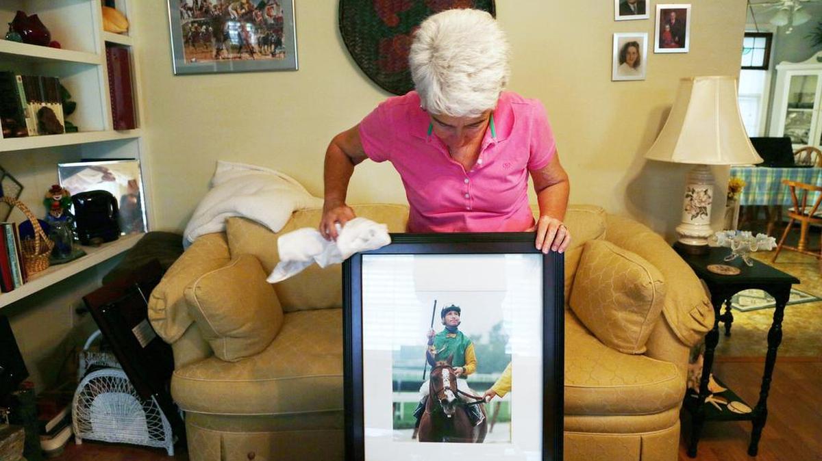 
Annie Antley, stepmother to the late jockey Chris Antley, cleans one of his photos as she talks about his career. 
